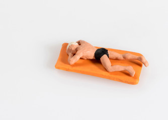 Miniature man in swimming costume lying sunbathing