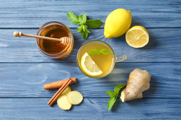 Cup with hot tea, lemon and ginger for cold on wooden table, top view