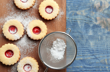Traditional Christmas Linzer cookies with sweet jam and sugar powder on wooden background, top view