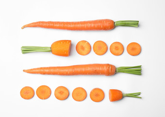 Whole and cut fresh carrots on white background