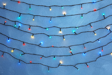 Beautiful bright Christmas lights on color background
