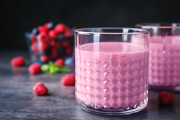 Delicious smoothie in glasses and fresh raspberries on table