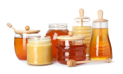 Glass jars with different types of sweet honey on white background