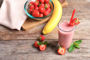 Glass with tasty strawberry smoothie on wooden table