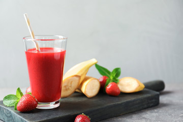 Glass with tasty strawberry smoothie and fresh fruits on wooden board