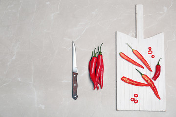 Flat lay composition with chili peppers on light background