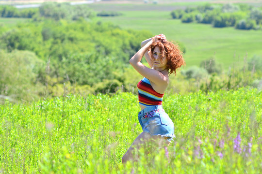Caucasian girl poses on camera outdoors on a summer meadow