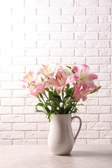 Beautiful blooming lily flowers near brick wall