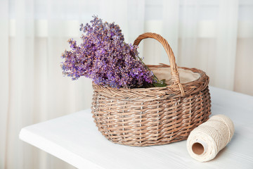 Fototapeta na wymiar Wicker basket with lavender flowers on table indoors