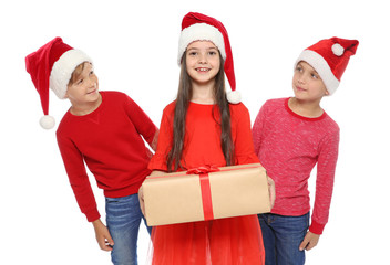 Cute little children in Santa hats with Christmas gift box on white background