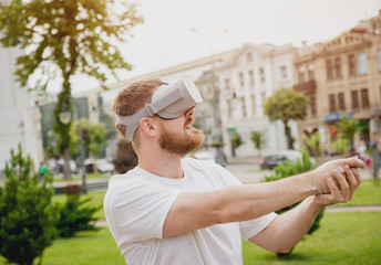 Fototapeta premium A young man plays a game wearing virtual reality glasses on the street.