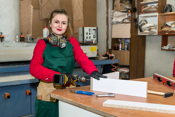 Woman carpenter with drill machine constructing furniture