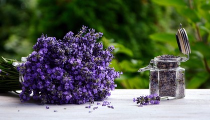 Bouquet of fresh lavender and dry lavender in a glass jar on a white table on the garden background.