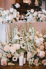 beautiful decoration of the newlyweds' table, flower arrangement of white and pink roses with buttercups, decorative candlesticks
