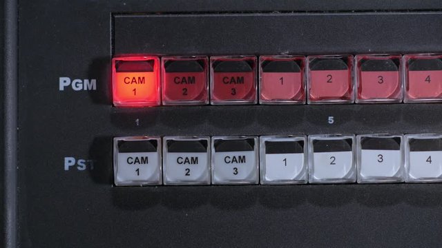 teledirector is switching on a camera, pushing key on a control panel in tv studio