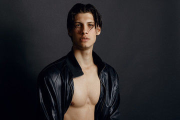 Male model in denim blue jeans and black leather jacket on black background
