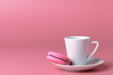 One pink macaroon with cup of coffee