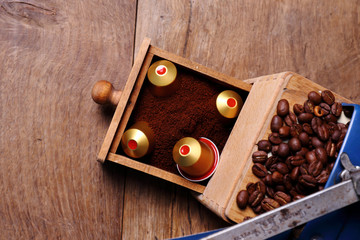 Top view Vintage manual coffee grinder with beans of coffee and capsules for espresso. Freshly ground coffee.  Concept of fresh coffee. Vacuum capsules nespresso. 