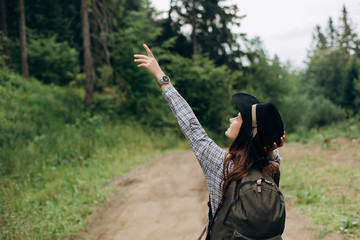 woman traveler, looking and pointing her hand at the wonderful forest, the concept of travelers, the place for the text, the atmospheric epic moment