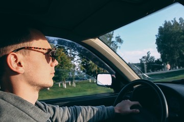 young male driver in sunglasses driving a car. Travel in the summer.