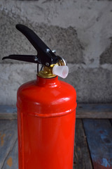 Compact red fire extinguisher for auto or home on grey background. For fire emergencies.