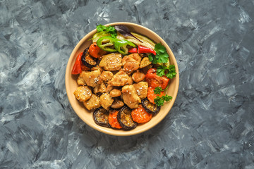 Pieces of baked meat with grilled vegetables on a plate.
