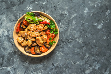Pieces of baked meat with grilled vegetables on a plate.

