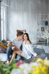 Obraz premium young multicultural couple sitting on bed in morning in bedroom