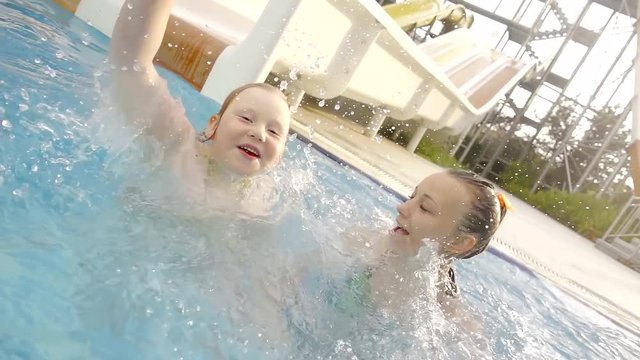 Two sisters having a fun holidays in the pool with big water slide.