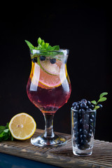 Cold summer homemade fruit and berries lemonade. Mojito, lemonade or sangria in glass. On dark background