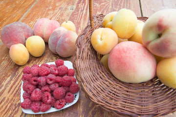 Fresh raspberry, peaches and Apricot in a wicker basket on wooden table