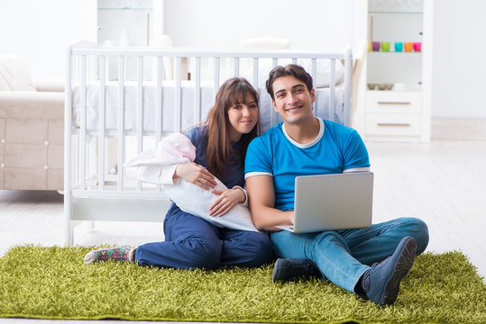 Young parents with their newborn baby sitting on the carpet 