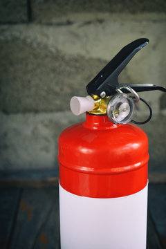 Compact red fire extinguisher for auto or home on grey background. For fire emergencies.
