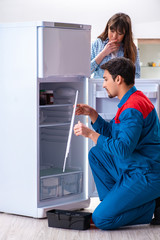 Man repairing fridge with customer
