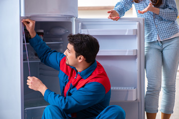 Fototapeta na wymiar Man repairing fridge with customer