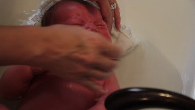 Newborn baby takes his first bath, and does not like it!