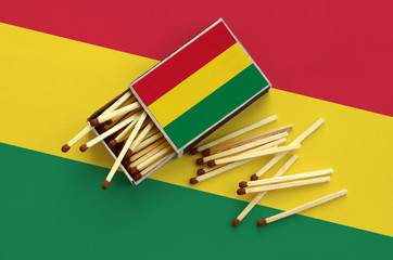 Bolivia flag  is shown on an open matchbox, from which several matches fall and lies on a large flag