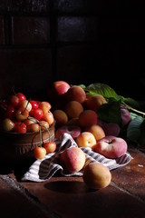 Sweet cherries, peaches, apricots and nectarines on a dark brick background.