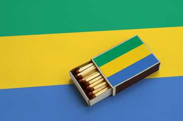 Gabon flag  is shown in an open matchbox, which is filled with matches and lies on a large flag