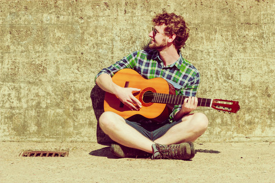 Young bearded hipster man with guitar outdoor