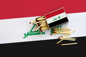 Iraq flag  is shown on an open matchbox, from which several matches fall and lies on a large flag