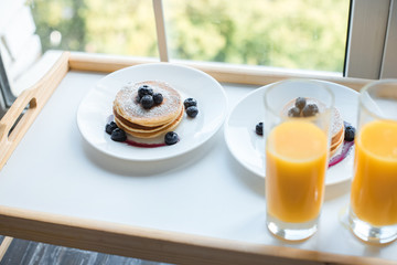 close up view of glass of juice and pancakes for breakfast on wooden tray