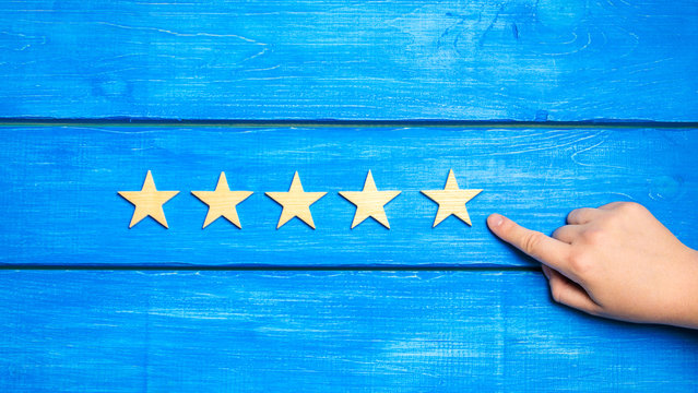 hand puts the fifth star. Quality status is five stars. A new star, achievement, universal recognition.The critic determines the rating of the restaurant, hotel, institution. Quality mark.