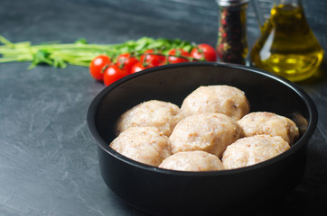 raw homemade steamed meatballs with chicken and buckwheat. black concrete background. place for text. copyspace