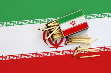 Iran flag  is shown on an open matchbox, from which several matches fall and lies on a large flag