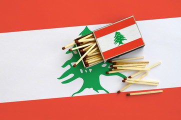 Lebanon flag  is shown on an open matchbox, from which several matches fall and lies on a large flag