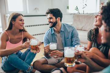 Friends eating popcorn and drinking beer mug at home, having fun.