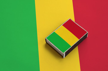 Mali flag  is pictured on a matchbox that lies on a large flag
