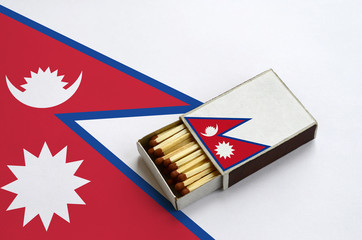 Nepal flag  is shown in an open matchbox, which is filled with matches and lies on a large flag