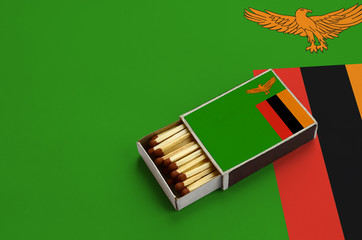 Zambia flag  is shown in an open matchbox, which is filled with matches and lies on a large flag